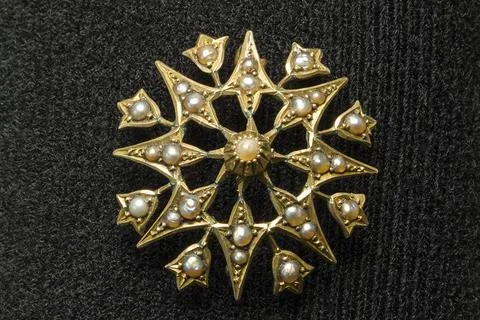 Golden snowflake brooch glints with tiny pearls Stock Photos