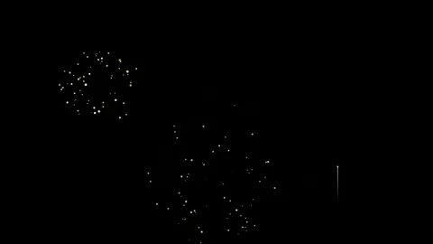 Golden sparkling fireworks exploding against a solid black background for Stock Footage 345427174