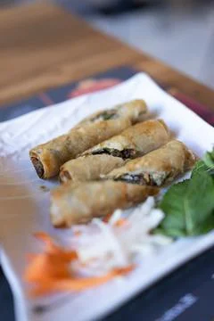 Golden spring rolls rest on a white plate Stock Photos