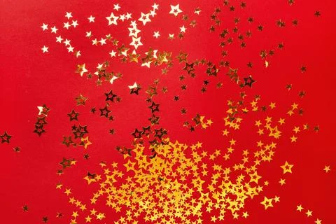 Golden stars confetti on red background. Christmas festive background Stock Photos