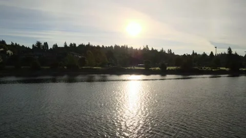 Golden Sun behind clouds over water reflection Lions Park Bremerton Kitsap Stock Footage 154984886