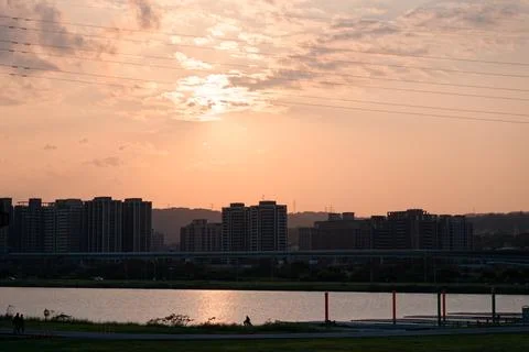 Golden Sun Breaking Through Clouds Above Riverside Towers and Power Lines Foto stock