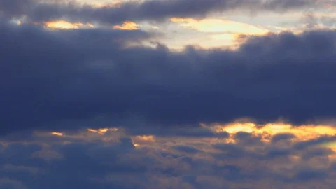Golden sun breaking through dark blue fluffy quickly passing clouds 4K Timelapse Stock Footage 106015580