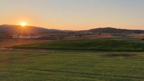 Golden sun dips behind distant hills, painting agricultural plains in warm .. Video stock 315162202