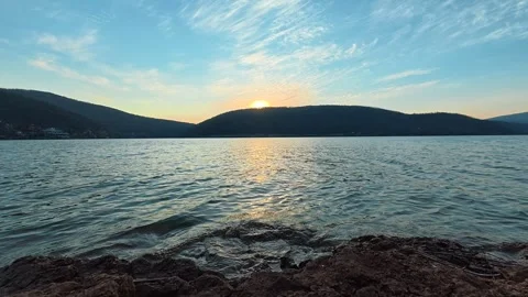 Golden sun dips low over calm lake waters . Bovan Lake Vidéo 330989435