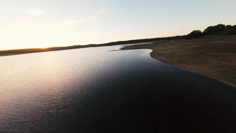 Golden sun dips low over calm lake surface at Pego do Altar Reservoir Stock Footage 342166447