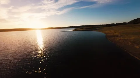 Golden sun dips low over calm water's edge at Pego do Altar Reservoir Stock Footage 342182970