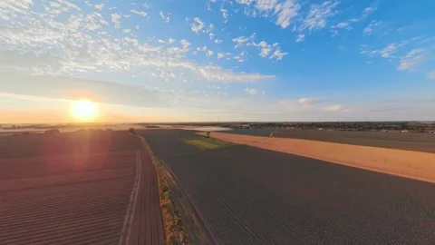 Golden sun dips low over vast, tilled fields 库存影片 342555374
