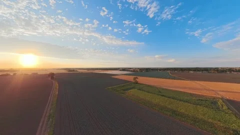 Golden sun dips low over vast, tilled fields Vidéo 342589734