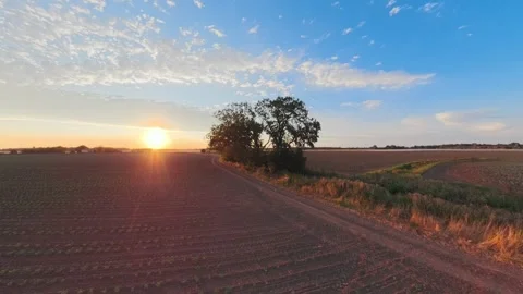 Golden sun dips low over tilled fields Stockbeeldmateriaal 342591323