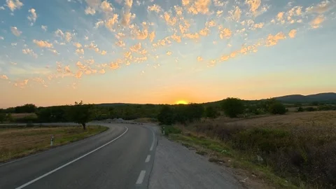 Golden sun dips low over winding country road. Serbia 動画素材 346249985