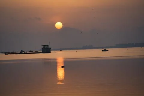 Golden sun dips low over calm waters Stock Photos