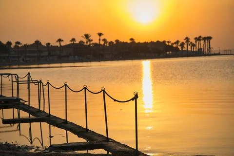 Golden sun dips low over calm waters Stock Photos