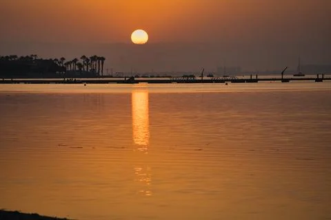 Golden sun dips low over calm waters Stock Photos