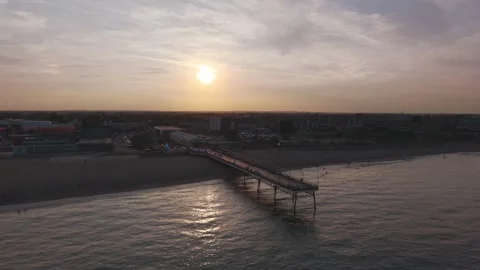 Golden sun dips over pier, casting long shadows on water Видео 342662568