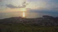 Golden sun drowning in sea at sunset, city lights timelapse, evening cloudscape 4k or 4k+ Resolution