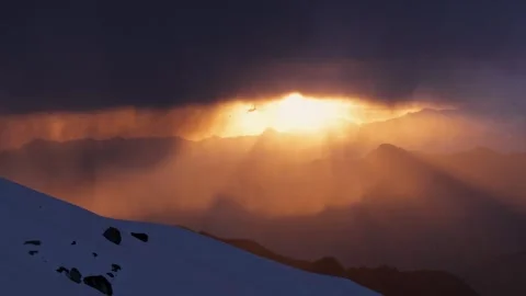 Golden Sun Rays Breaking Through Dark Clouds Over a Snowy Himalayan Ridge Stock Footage 345368623