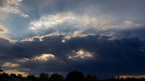 Golden sun rays breaking through dark clouds Stock Photos