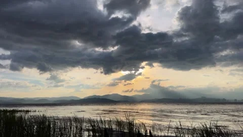 Golden Sun Rays Pierce Dramatic Clouds Over Mountain Lake in Yunnan China Stock Footage 339232965
