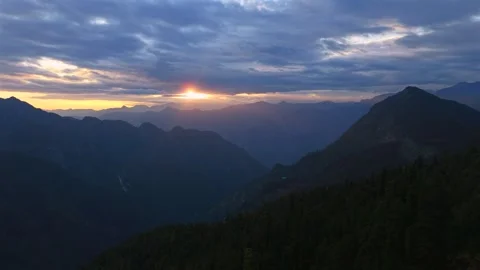 Golden sun rays piercing through clouds above layered Himalayan mountains near Stock Footage 336590260