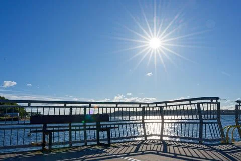 Golden sun rays spreading over bridge rail and calm sea at kiel Stock Photos