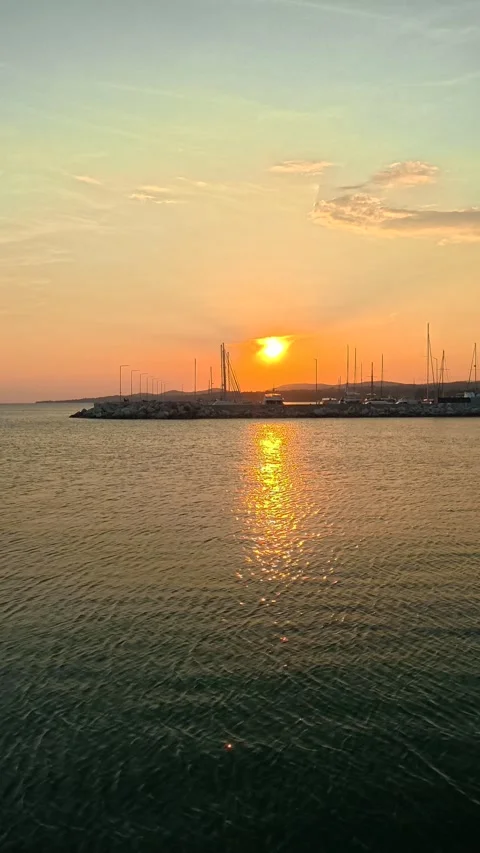 Golden sun sets over calm harbor waters. Nikiti, Greece. Vertical Stock Footage 338357698