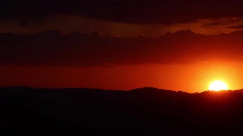 Golden sun sets over mountain silhouette, casting a vibrant orange glow. Stock Footage 305140144
