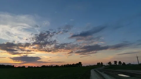 Golden sun setting behind dark forest under a blue sky Stock Footage 335716771