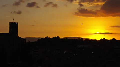 Golden Sun Setting Behind Tower Silhouette with Clouds and Distant Hills Vídeo Stock 256219574