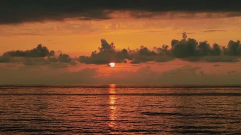 Golden Sun Setting Between Dark Clouds Over Calm Ocean Horizon Stock Footage 331834856