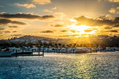 Golden sun setting into clouds over marina Stock Photos