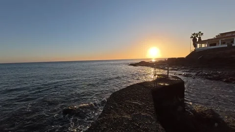 Golden sun setting over a calm rocky coastline Stock Footage 334636355