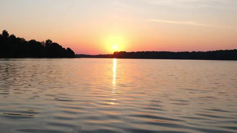 Golden sun setting over a calm lake. Peaceful evening landscape with orange sky Vidéo 340356238