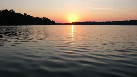 Golden sun setting over a calm lake. Peaceful evening landscape with orange sky Vidéo 340356909