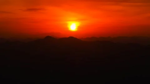 Golden sun setting over distant mountain peaks with fiery sky and silhouettes Stock Footage 316523189