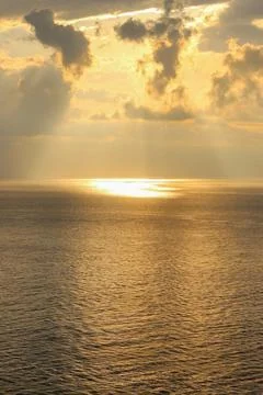 Golden Sunbeams Breaking Through Clouds Over Ocean Horizon 库存照片