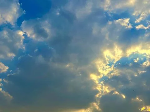 Golden Sunbeams Breaking Through Dramatic Clouds in a Scenic Blue Sky View Stock Photos