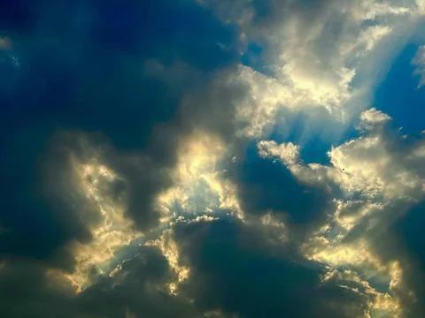 Golden sunlight breaking through dark overcast clouds during a vibrant sunset Foto stock