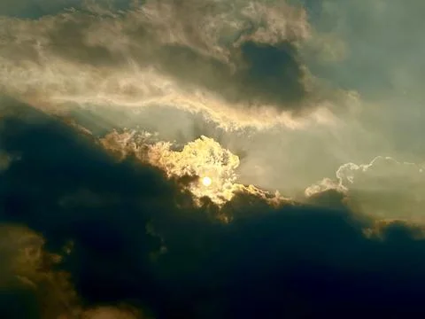 Golden sunlight breaking through dark dramatic storm clouds in atmospheric Stock Photos