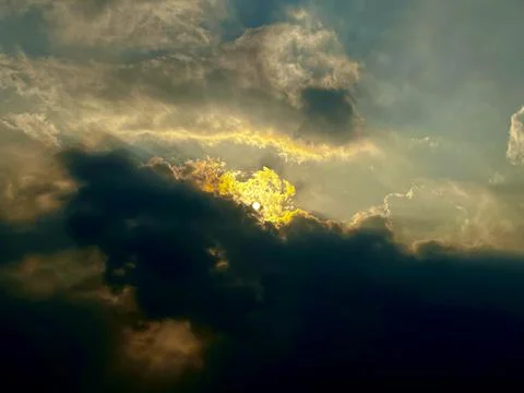 Golden sunlight breaking through dark dramatic storm clouds in atmospheric Foto stock