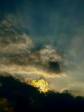 Golden sunlight breaking through dark dramatic storm clouds in atmospheric Stock Photos