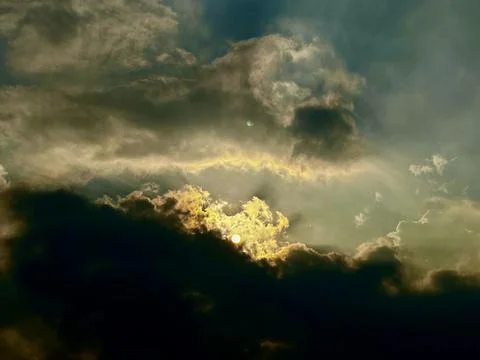 Golden sunlight breaking through dark dramatic storm clouds in atmospheric Stock Photos