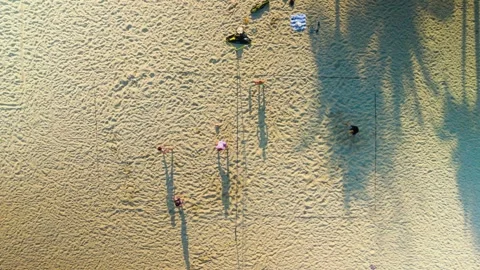 Golden sunlight casting long shadows across sandy coastline, silhouetted Stock Footage 300244411