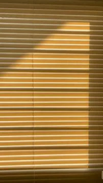Golden sunlight casts diagonal shadows across tightly closed horizontal win.. Stock Photos