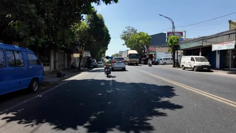 Golden sunlight filters down a lively urban street, where cars glide smoothly Stock Footage 345160160
