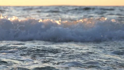 Golden sunlight reflecting on ocean waves crashing during a sunset Stock Footage 337416789