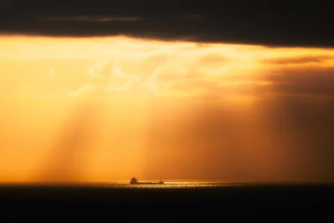 Golden sunrays on the ocean with a ship Stock Photos