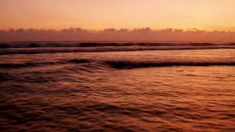 Golden sunset bathes the ocean waves along a sandy beach Stock Footage 312677743