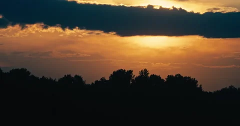 Golden Sunset Behind Dark Clouds Above Silhouetted Tree Line Stock Footage 340856209
