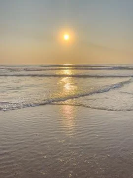 Golden sunset casting a brilliant reflection over gentle ocean waves washin.. Stock Photos